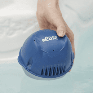 A person is holding a FROG @Ease Floating Sanitizing System for Hot Tubs in the water.